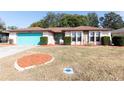 Front view of a ranch home with a teal garage door and neat landscaping at 12609 Shadow Ridge Blvd, Hudson, FL 34669