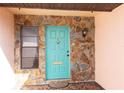 Charming teal front door with stone accents and a brass knocker at 12609 Shadow Ridge Blvd, Hudson, FL 34669