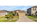 Front view of a charming house with a two-car garage, neat landscaping, and a wide driveway at 16644 Sunburst Lake St, Wimauma, FL 33598