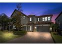 Night view of two-story house with a three-car garage and paver driveway at 17907 Woodland View Dr, Lutz, FL 33548