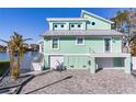 Two-story light teal home with metal roof and paved driveway at 17410 1St E St, Redington Shores, FL 33708