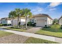 Tan house with a two-car garage and palm trees at 15314 Valencia Del Sol St, Wimauma, FL 33598