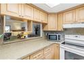 Kitchen with light wood cabinets, granite countertops, and view to living room at 2400 Winding Creek Blvd # 24-203, Clearwater, FL 33761