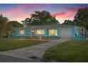 Charming, bright blue single-story home with a well-manicured front lawn in the early evening at 6500 7Th S Way, St Petersburg, FL 33705