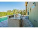 Poolside outdoor kitchen featuring a granite counter, tile backsplash, and stainless steel grill at 5709 White Trillium Loop, Land O Lakes, FL 34639