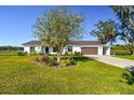 White single story home with brown metal roof, landscaping and a two car garage at 8215 Cosme Rd, Odessa, FL 33556