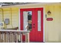 Red front door entry to a yellow home with wooden railings at 13515 Gavin Rd, Dover, FL 33527