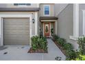 Townhome entry with orange door and neatly landscaped walkway at 31639 Blue Passing Loop, Wesley Chapel, FL 33545