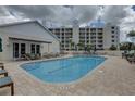 Community pool with surrounding patio furniture and building view at 1200 Country Club Dr # 2504, Largo, FL 33771