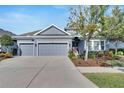 Single-story home with gray exterior, three-car garage, and landscaped yard at 7506 Parkshore Dr, Apollo Beach, FL 33572