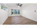 Bright bedroom featuring a large window with a view of the lake, a ceiling fan, and hardwood floors at 905 Lake Fuller Dr, Lutz, FL 33548