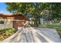 Attached two-car garage with a large tree providing shade and a view of the lake in the background at 905 Lake Fuller Dr, Lutz, FL 33548
