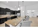 Modern kitchen featuring dark wood cabinets, granite countertops, stainless steel appliances, and a breakfast bar at 11926 Cinnamon Fern Dr, Riverview, FL 33579