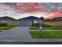 One-story house with gray siding, two-car garage, and landscaped yard at sunset at 4005 Langdrum Dr, Wesley Chapel, FL 33543