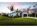 Single-story house with a light-colored exterior, palm trees, and a grassy lawn at 141 Hobo Rd, Rotonda West, FL 33947