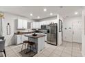 Well-lit kitchen featuring white cabinetry, stainless steel appliances, and a central island with bar stools at 5193 Deltona Blvd, Spring Hill, FL 34606