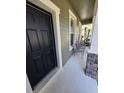 Inviting front porch featuring a black front door, seating, and charming stone accents at 8451 Karpeal Dr, Sarasota, FL 34238