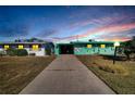 Evening view of a mint green house with carport and landscaping at 1535 Council Dr, Sun City Center, FL 33573