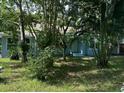 Light blue house nestled among tropical foliage, showcasing curb appeal at 1714 2Nd E Ave, Bradenton, FL 34208