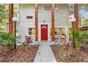 Inviting front porch with a bright red door, wooden columns, and lush landscaping at 807 E Genesee St # 1/2, Tampa, FL 33603