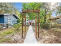 Wooden arbor frames the walkway to the charming home with a red door at 807 E Genesee St # 1/2, Tampa, FL 33603