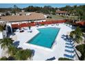 Community pool with lounge chairs, umbrellas, and surrounding buildings at 303 Knottwood Ct # 3, Sun City Center, FL 33573