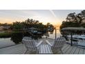 Relaxing outdoor deck with chairs, overlooking a serene waterfront at sunset at 5004 W Leona St, Tampa, FL 33629