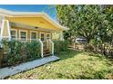 Front view of a yellow house with a porch and landscaping at 809 E Lambright St, Tampa, FL 33604