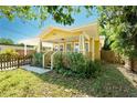 Charming yellow house with a porch, fenced yard, and mature trees at 809 E Lambright St, Tampa, FL 33604