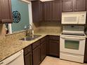 Well-equipped kitchen with granite countertops, dark cabinets, and stainless steel appliances at 3480 Hillmoor Dr, Palm Harbor, FL 34685