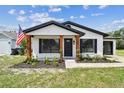 Inviting home with black trim, an American flag, and fresh landscaping, offering great curb appeal at 102 Shore E Dr, Oldsmar, FL 34677