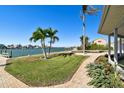 Landscaped backyard with brick pathway, lush lawn, and waterfront access at 568 Johns Pass Ave, Madeira Beach, FL 33708