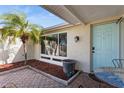 Inviting front porch featuring a paver patio, small palm tree, and light blue front door at 9830 Mark Twain Ln, Port Richey, FL 34668