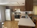 Compact kitchen featuring white appliances, wood cabinetry, and tile flooring at 2165 Corbin Pl # A, Palm Harbor, FL 34683