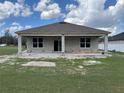 The backyard features a covered patio with block columns, a green lawn and sliding glass doors into the home at 413 Shannon Estates Ct, Plant City, FL 33563