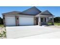 Charming exterior featuring a three-car garage, light gray stucco, brick accents, and concrete driveway at 413 Shannon Estates Ct, Plant City, FL 33563