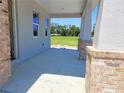 Inviting covered porch with brick columns and peaceful views of the surrounding landscape at 413 Shannon Estates Ct, Plant City, FL 33563