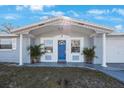 Charming gray house with blue front door, white columns and brick accents at 4304 Woodfield Ave, Holiday, FL 34691