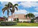 Front view of a two-story house featuring palm trees and a manicured lawn at 107 17Th St, Belleair Beach, FL 33786
