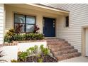 Front entrance with brick steps, blue door, and lush tropical landscaping at 107 17Th St, Belleair Beach, FL 33786