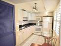 Compact kitchen with white cabinets, dark countertops, white appliances, and a small dining area at 920 Virginia St # 204, Dunedin, FL 34698
