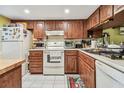 Kitchen featuring wood cabinets, white appliances, and tile flooring at 11511 113Th St # 27C, Largo, FL 33778