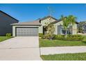 Charming single Gathering home featuring a gray garage door, green lawn, and decorative bushes at 13388 Great Plains Dr, Riverview, FL 33579