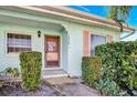 Front view of a light blue house with a wooden storm door, shrubs and palm trees at 2465 Northside Dr # 1808, Clearwater, FL 33761
