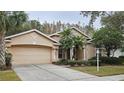 Two-story house with beige exterior, double garage, and palm trees at 6013 Catlin Dr, Tampa, FL 33647