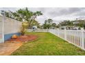 Landscaped backyard with a large grassy area and white fence at 6321 Staunton Dr, Holiday, FL 34690