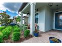 Covered front porch with two wooden chairs and potted plants at 21361 Snowy Orchid Ter, Land O Lakes, FL 34637