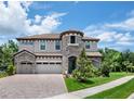 Stunning two-story home with a turret, tile roof, brick driveway, and well-maintained landscaping at 13019 Paddock Wood Pl, Riverview, FL 33579