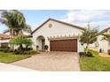 This home features a brick driveway, arched entryway, and a two-car garage with a stylish pergola above at 16831 Banner Shell Pl, Wimauma, FL 33598