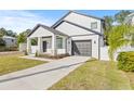 White two-story house with a covered porch, landscaping, a driveway, and a fenced yard at 3006 E Columbus Dr, Tampa, FL 33605